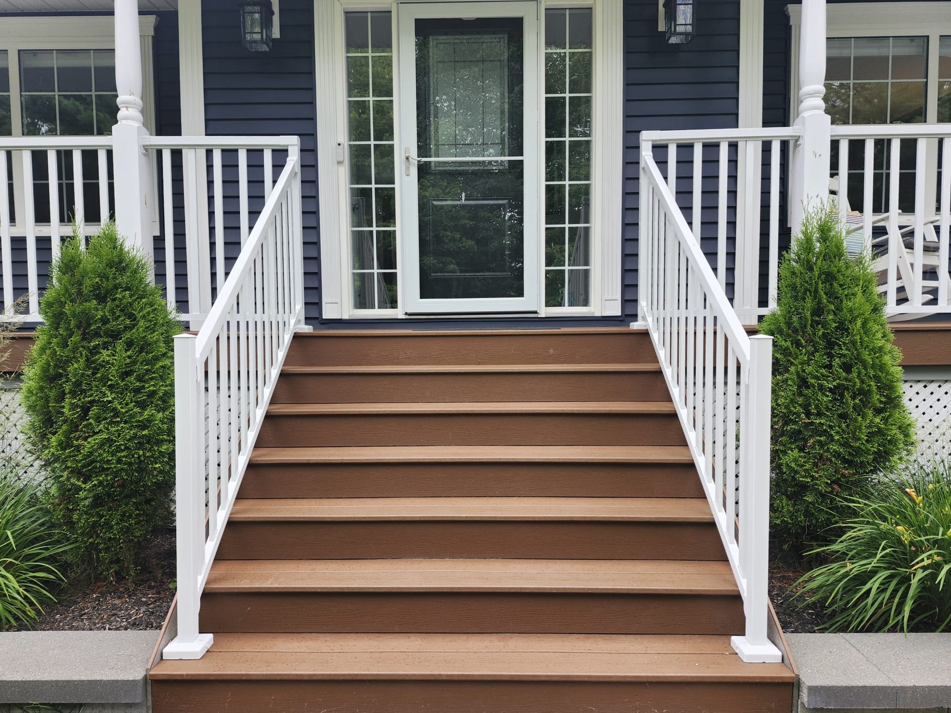 Deck stairs with brown composite boards and white railings by Wildstone